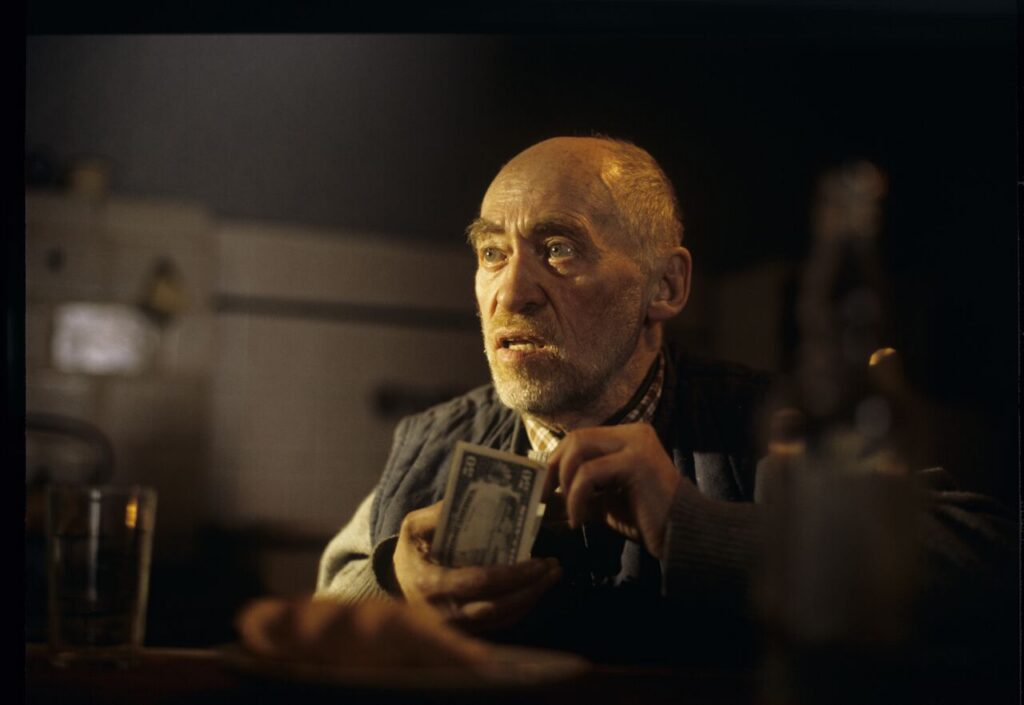 An old farmer (Jerzy Nowak) counts the money he earned from selling the land to Karol.
