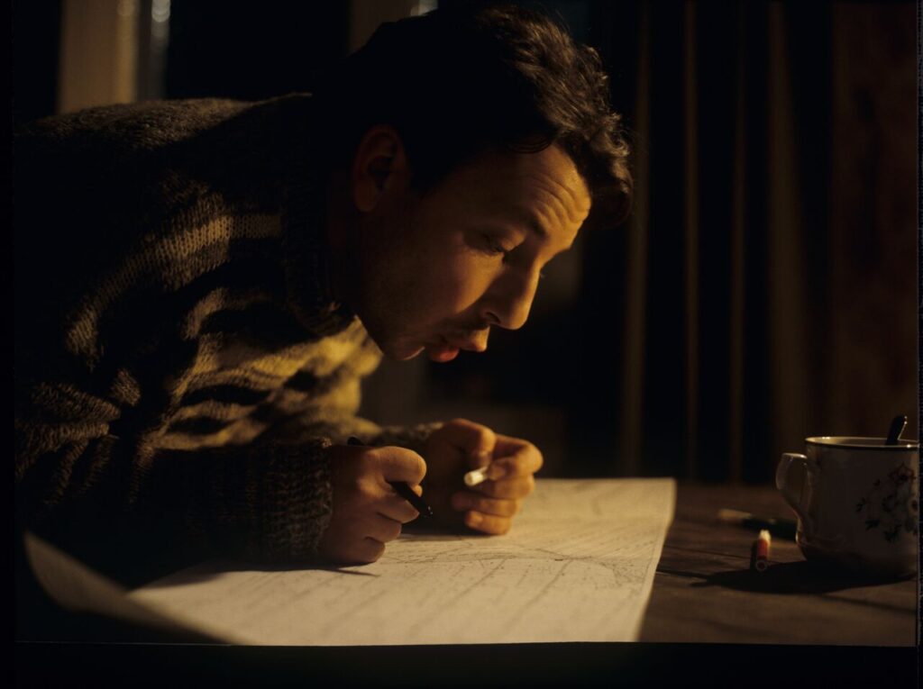 Karol (Zbigniew Zamachowski) looking at pland of lands he purchased.