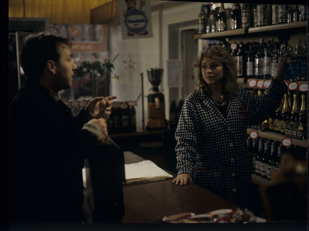 Karol (Zbigniew Zamachowski) buys alcohol to help him persuade the host to sell the land.