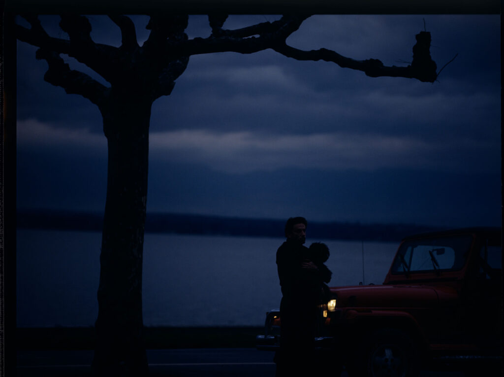 Auguste (Jean-Pierre Lorit) z psem przy samochodzie.