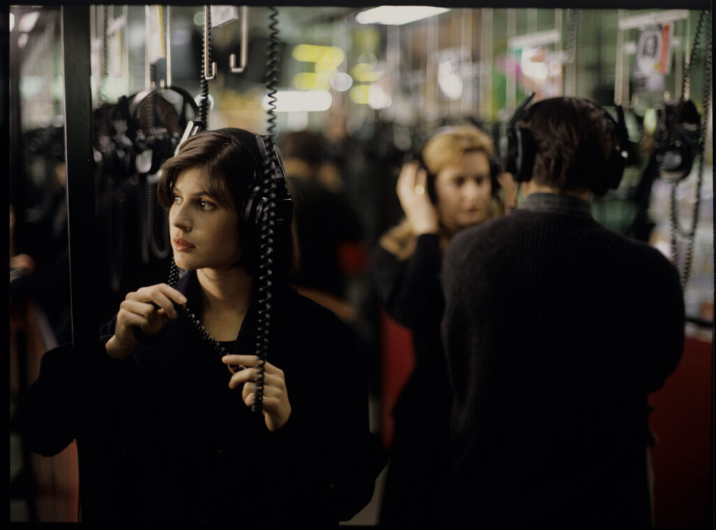 Valentine (Irène Jacob) listens to a record by Dutch composer Van den Budenmayer (Zbigniew Preisner) in a music store.