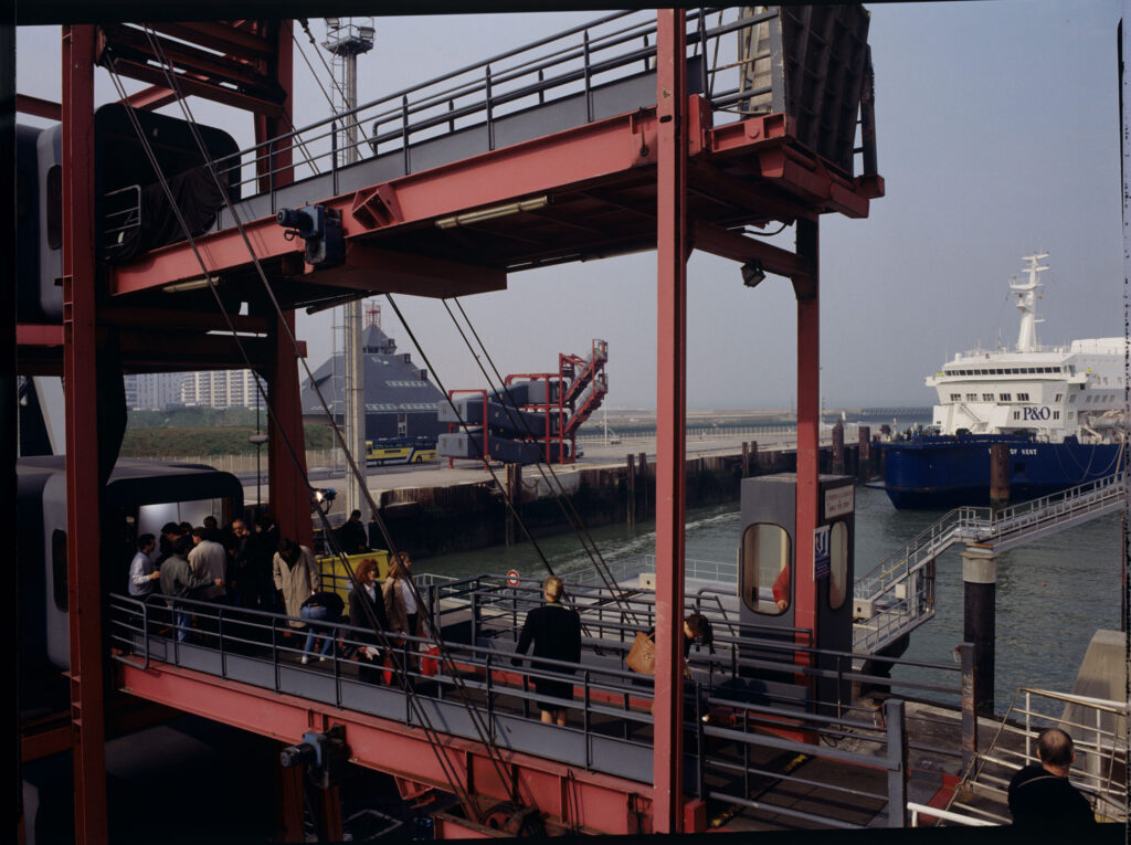 A scene on the docks. Passengers are boarding a ferry that will soon sail to England.