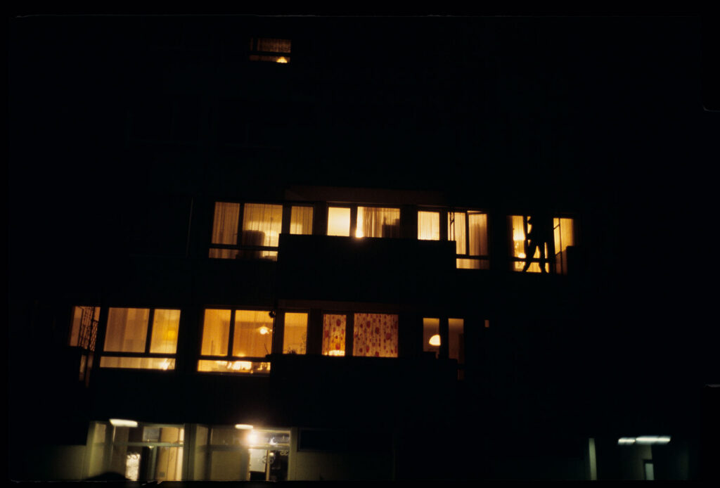 Auguste (Jean-Pierre Lorit) climbs the facade of a building to look through the window into his girlfriend's apartment.