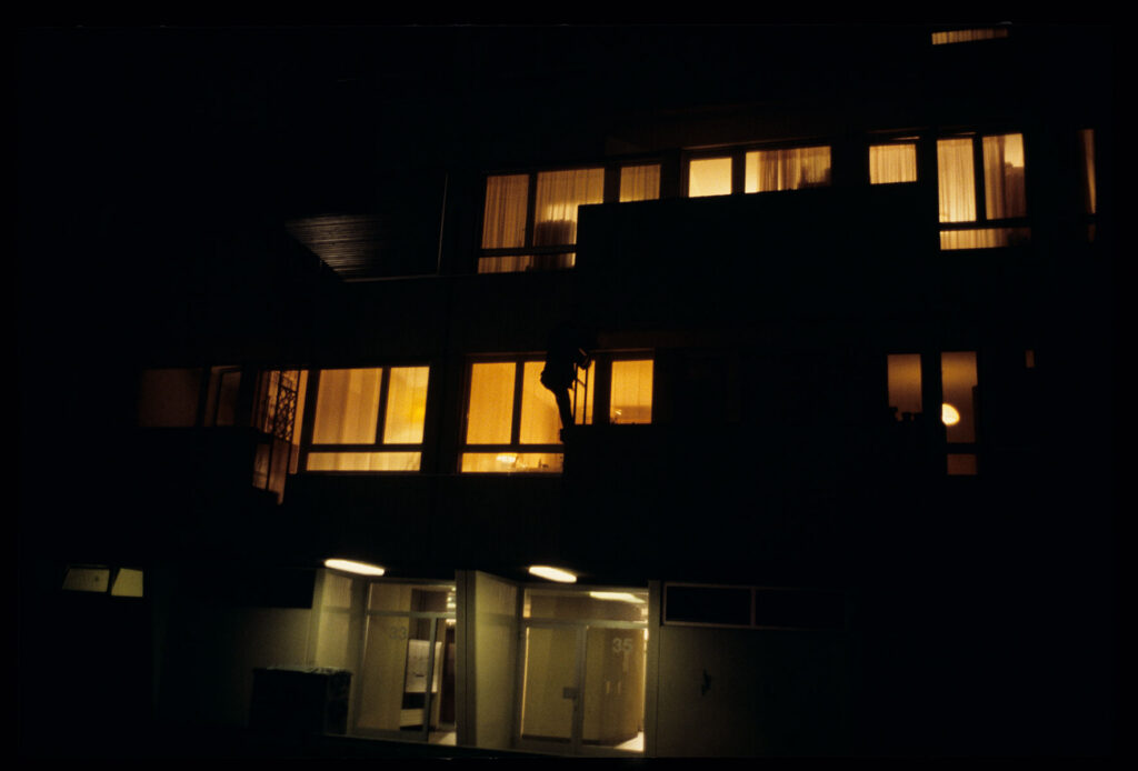 Auguste (Jean-Pierre Lorit) climbs the facade of a building to look through the window into his girlfriend's apartment.