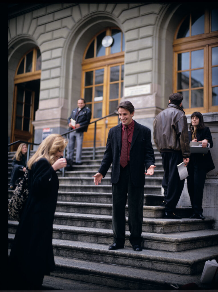 Auguste (Lorit), po zdaniu egzaminów, spotyka się ze swoją partnerką Karin (Feder) przed gmachem genewskiego sądu.