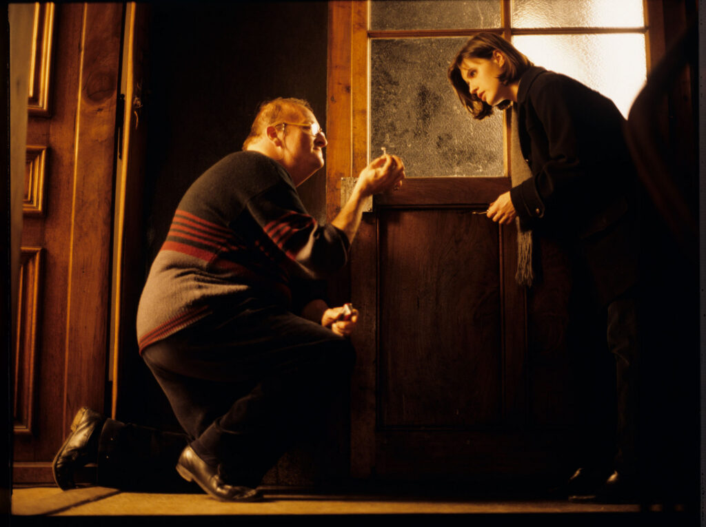 Valentine (Jacob) can't get into her apartment because the lock is stuck with chewing gum. A neighbor (Schlegel) helps her.