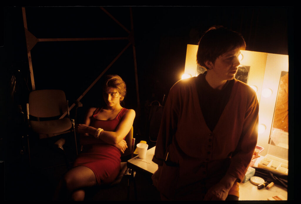 A makeup artist and model during a break during the filming of a fashion show in a theater.
