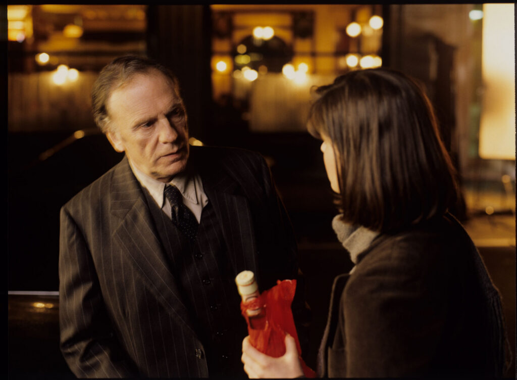 After the fashion show, retired judge Kern (Trintignant) presents Valentine (Jacob) with a bottle of Calvados.