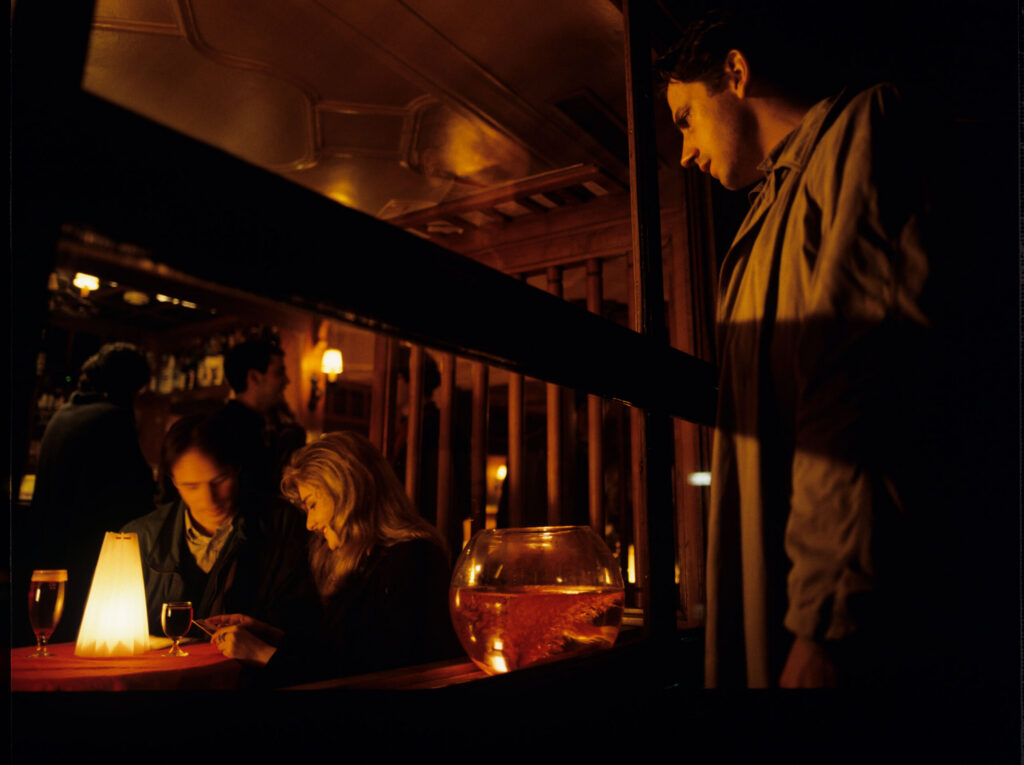 Auguste (Jean-Pierre Lorit) sees his partner Karin (Frederique Feder) with another man through the window of a café.