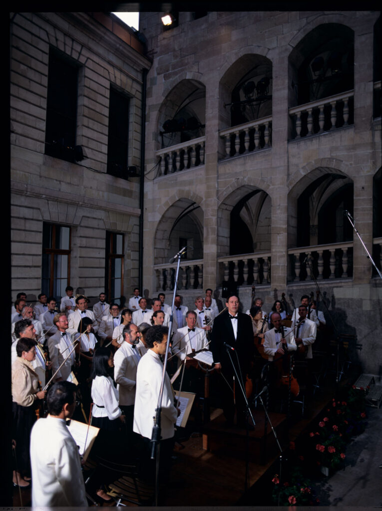 A photograph of the composer Patrice de Courcy (Hugues Quester) rehearsing with the orchestra.