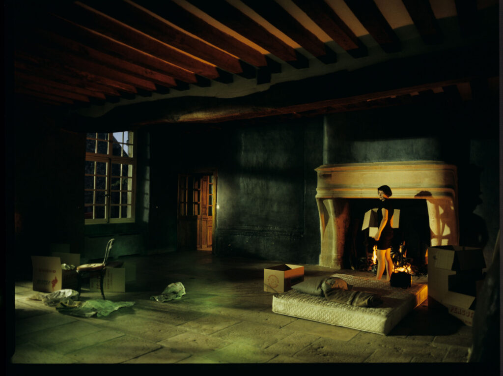 Julie (Juliette Binoche) in front of the fireplace in her large house near Paris.