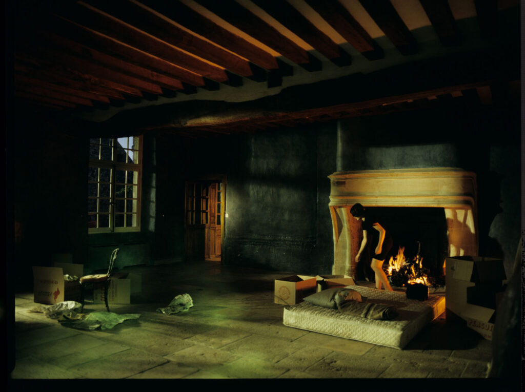 Julie (Juliette Binoche) in front of the fireplace in her large house near Paris.