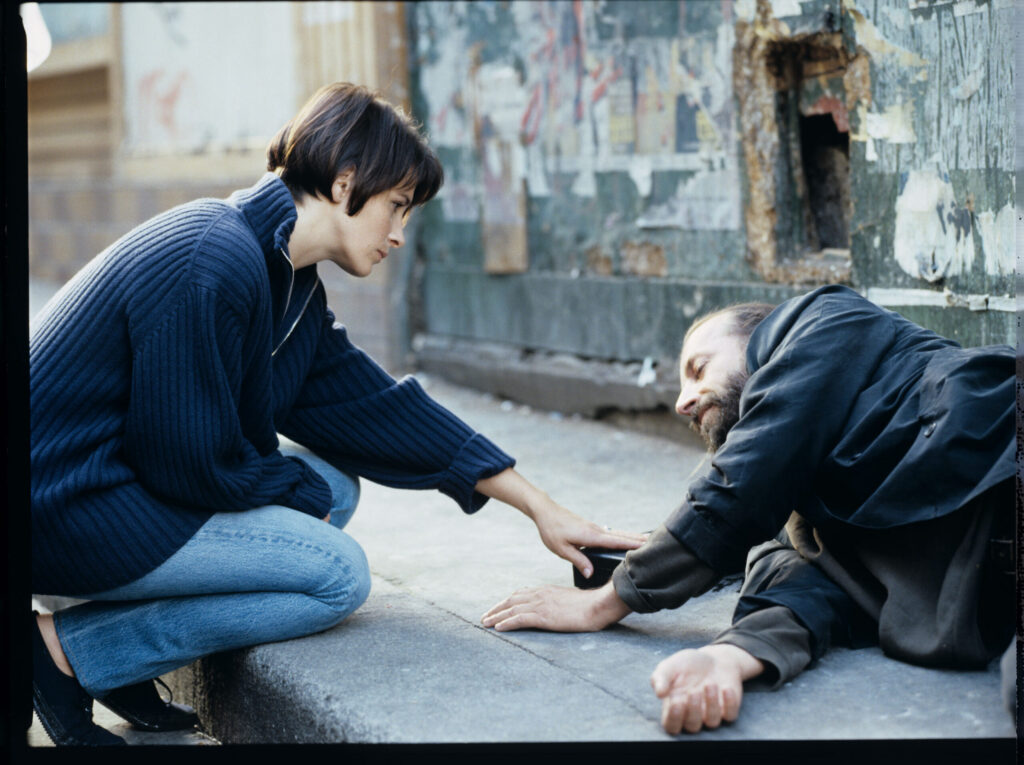 Julie (Juliette Binoche) talks to a street flautist (played by Jacek Ostaszewski - Polish composer and jazz musician).