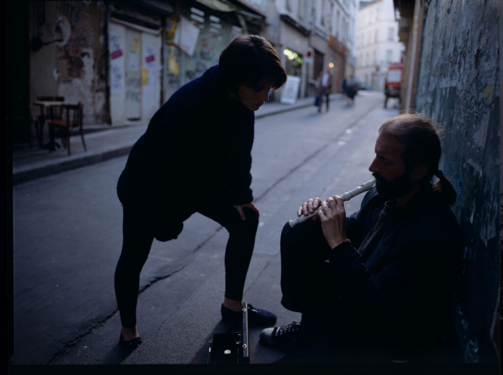 Julie (Juliette Binoche) talks to a street flautist (played by Jacek Ostaszewski - Polish composer and jazz musician).