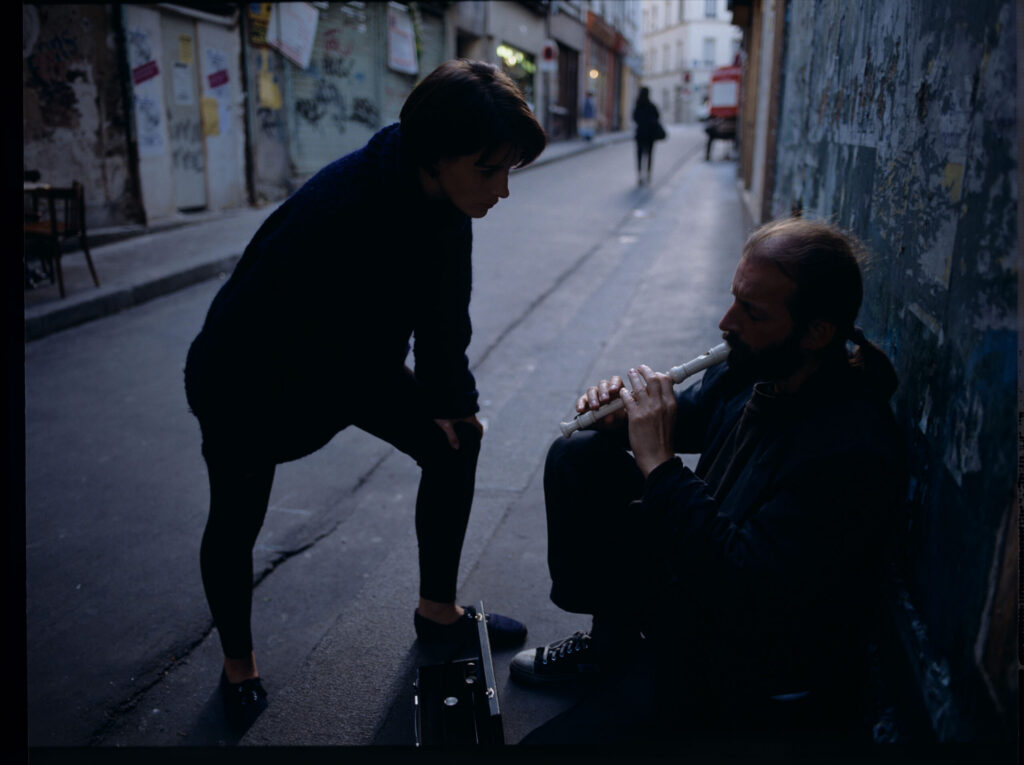 Julie (Juliette Binoche) talks to a street flautist (played by Jacek Ostaszewski - Polish composer and jazz musician).
