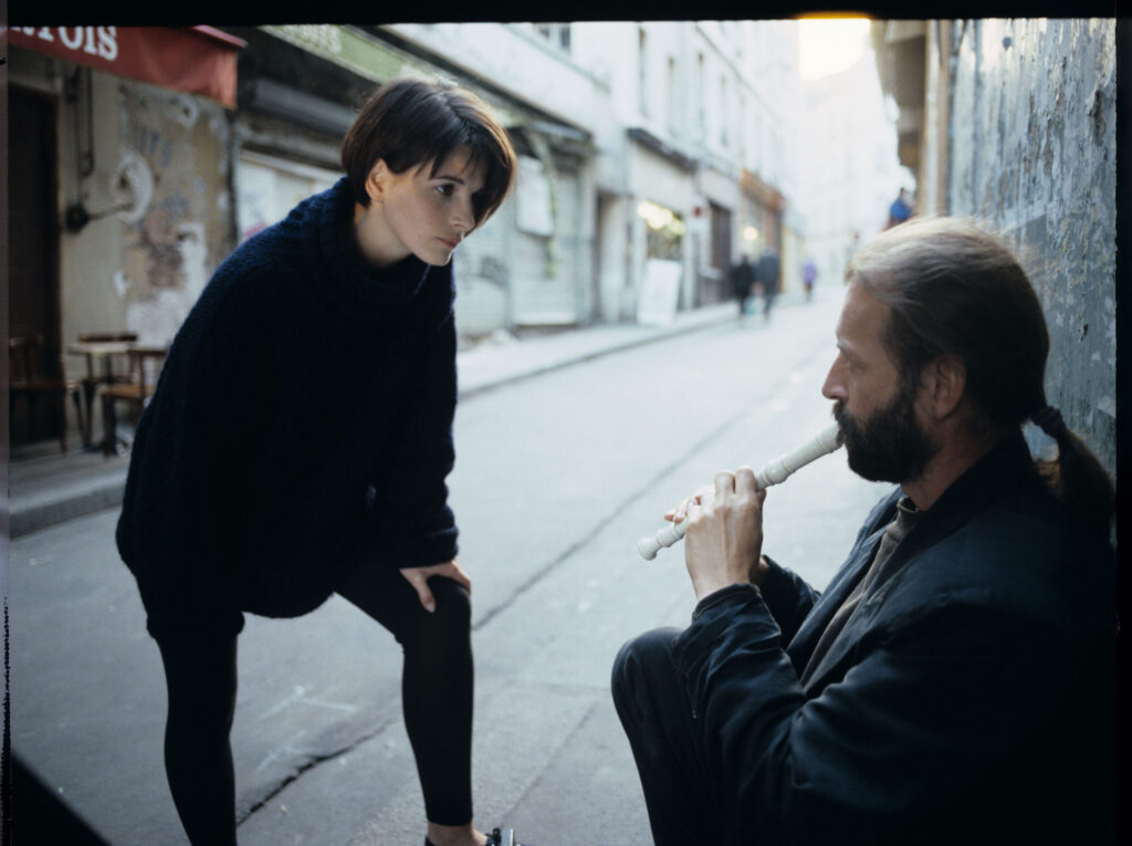 Julie (Juliette Binoche) talks to a street flautist (played by Jacek Ostaszewski - Polish composer and jazz musician).