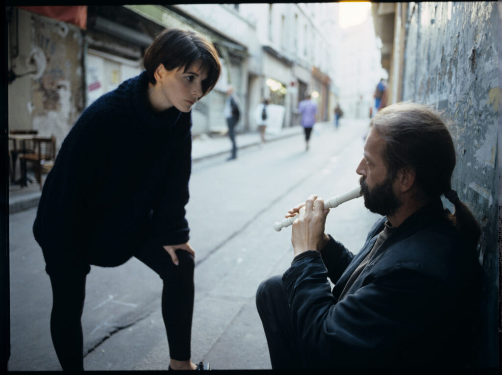 Julie (Juliette Binoche) talks to a street flautist (played by Jacek Ostaszewski - Polish composer and jazz musician).