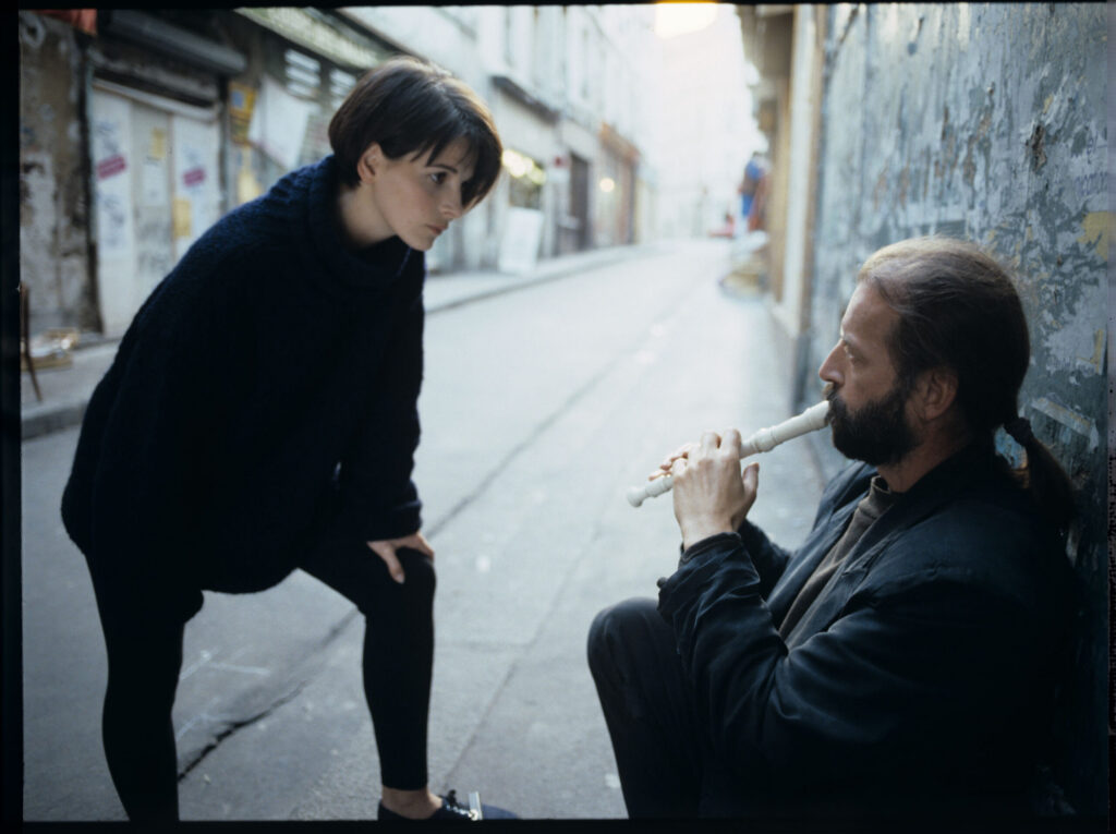 Julie (Juliette Binoche) talks to a street flautist (played by Jacek Ostaszewski - Polish composer and jazz musician).