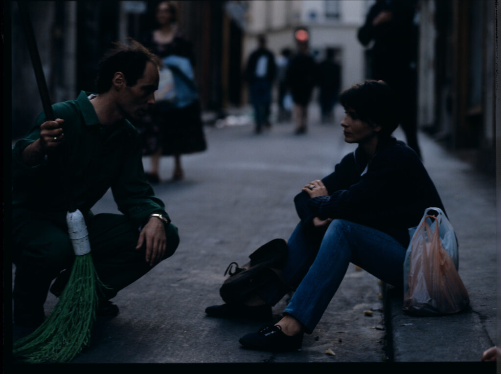 Siedząca na chodniku Julie (Juliette Binoche) rozmawia ze sprzątaczem ulic. Scena nie ukazała się w filmie.