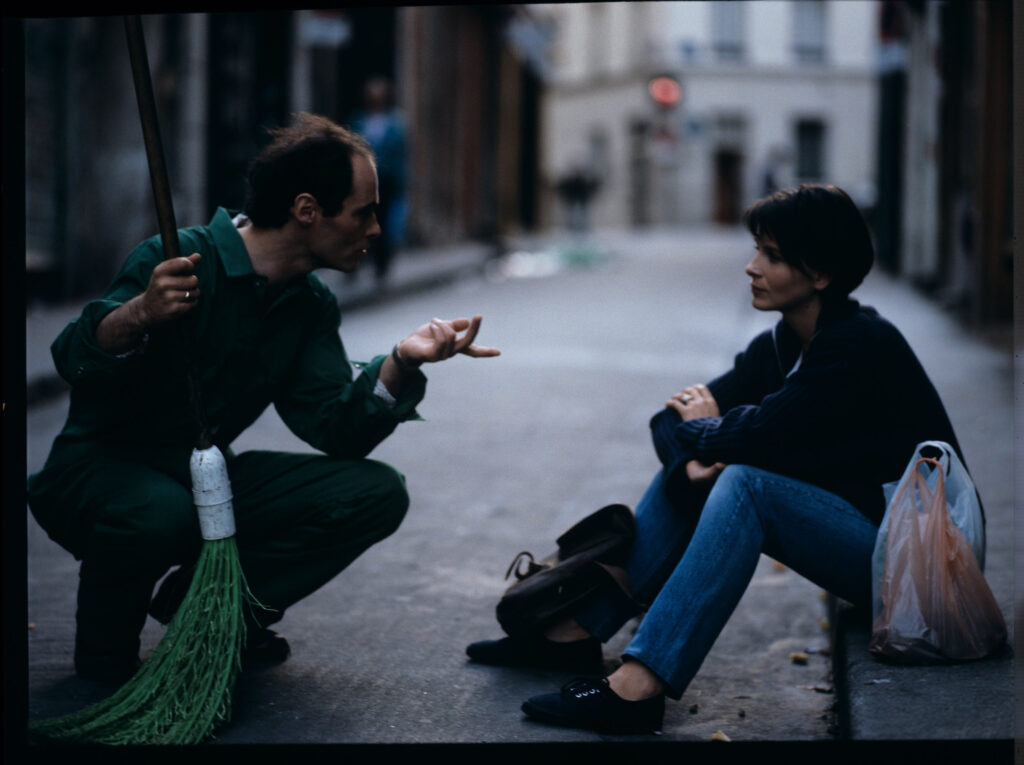 Siedząca na chodniku Julie (Juliette Binoche) rozmawia ze sprzątaczem ulic. Scena nie ukazała się w filmie.