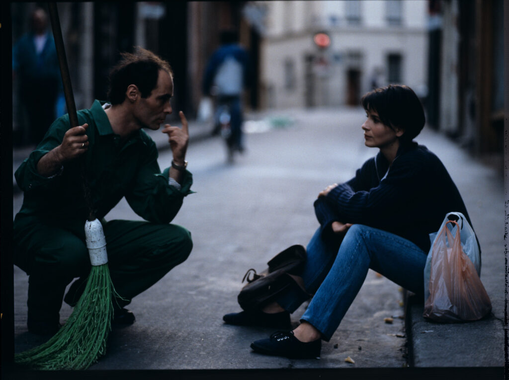 Siedząca na chodniku Julie (Juliette Binoche) rozmawia ze sprzątaczem ulic. Scena nie ukazała się w filmie.