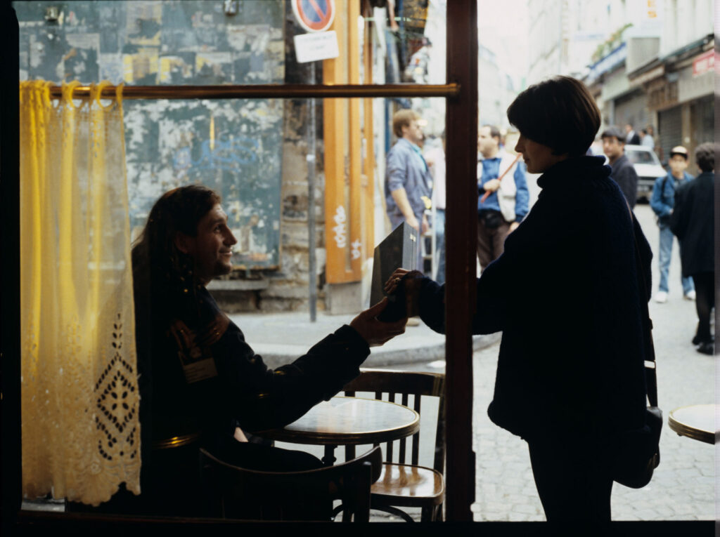 Julie (Juliette Binoche) in front of a café on a Parisian street. The scene did not appear in the film.