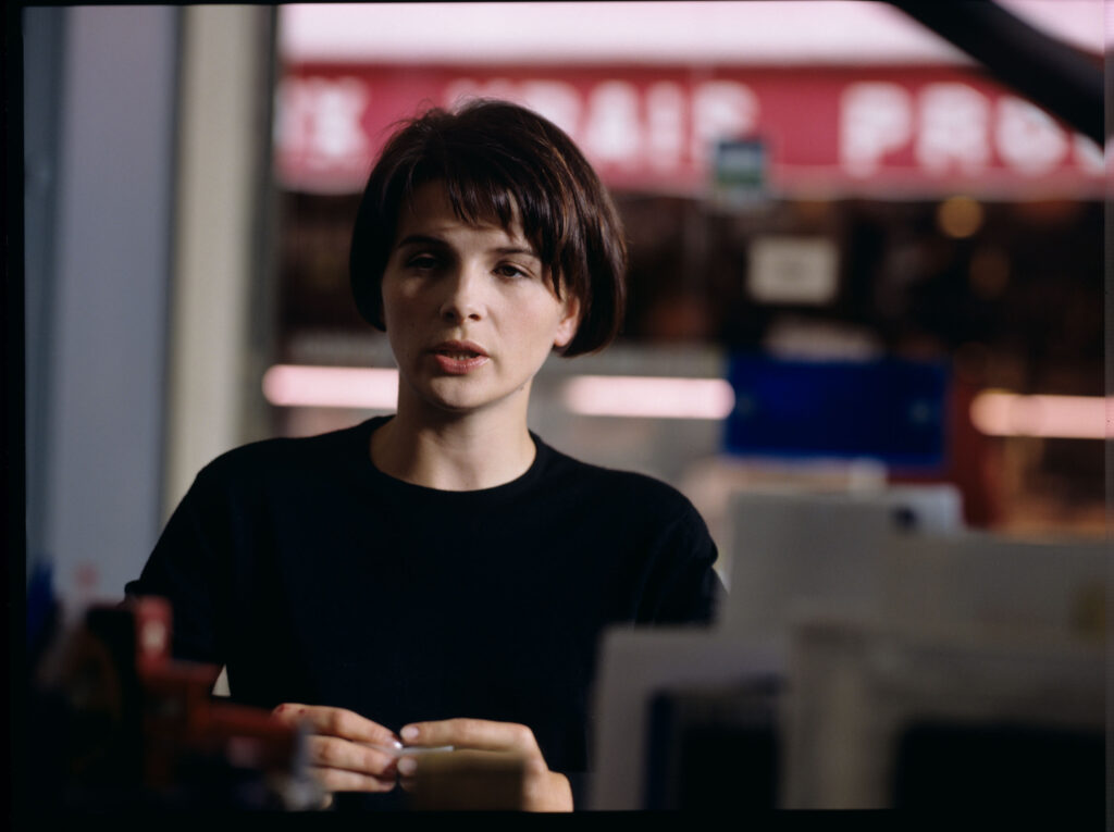 Julie (Juliette Binoche) siedząca w kawiarni przy ulicy, na której mieszka.