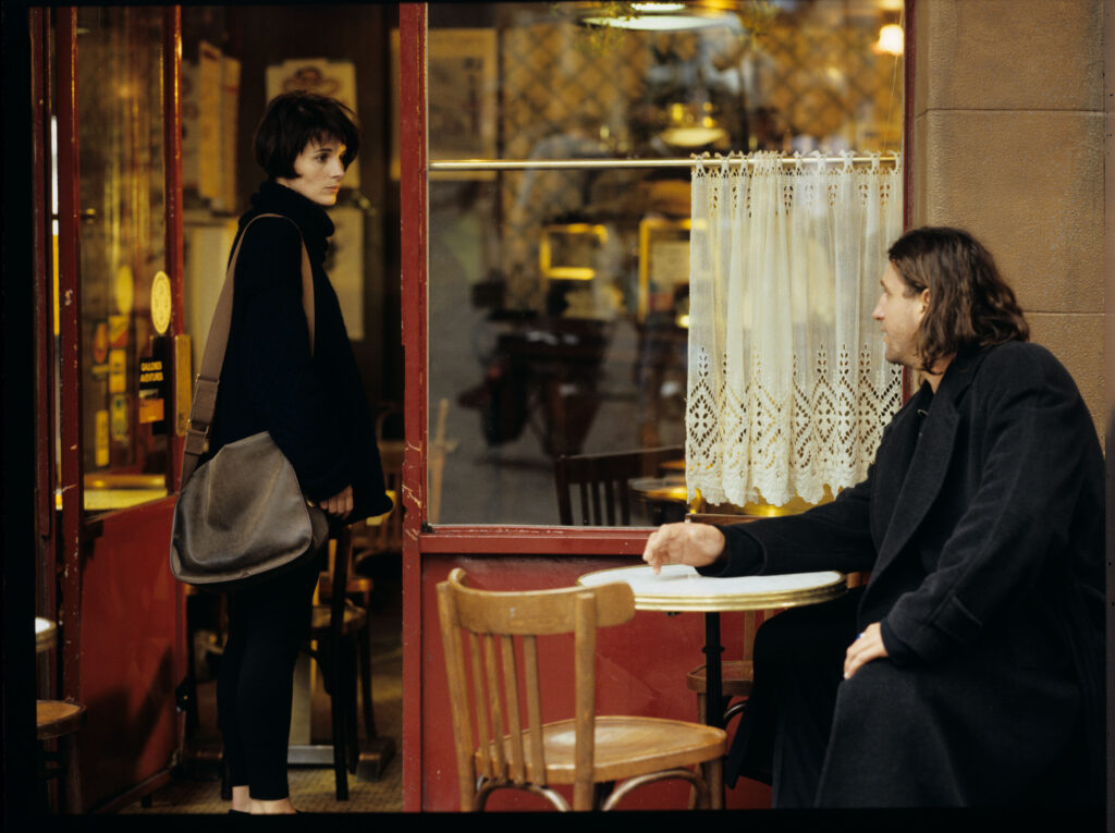 Julie (Juliette Binoche) rozmawia przed kawiarnią z długowłosym mężczyzną. Scena nie ukazała się w filmie.