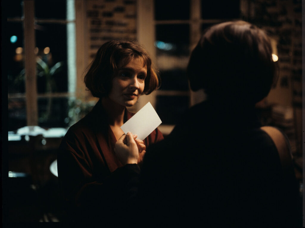The copyist (Florence Vignon) gives Julie (Juliette Binoche) a business card with Oliver's address and telephone number.
