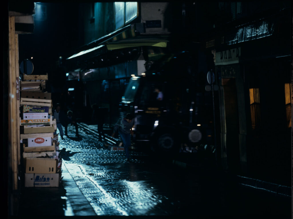 A man running away from attackers on the street under the windows of the main character of the film.