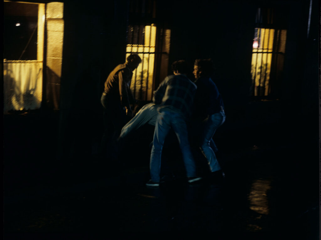 A scene of a street fight which the terrified Julie observes through the window of her apartment.