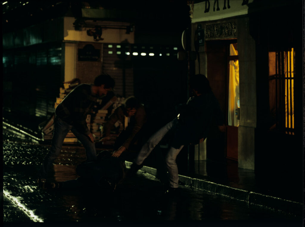 A scene of a street fight which the terrified Julie observes through the window of her apartment.