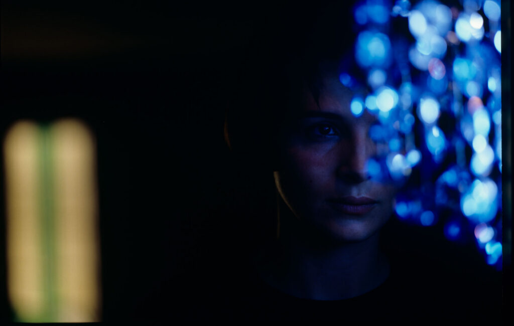 Fotos presenting the main character Julie (Juliette Binoche) looking at the blue chandellier.