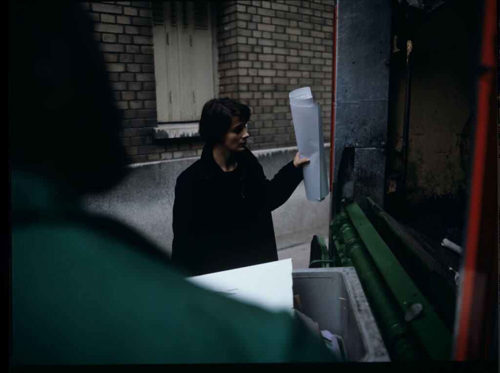 Julie (Juliette Binoche) throws sheet music into the garbage truck with an unfinished composition of her deceased husband.