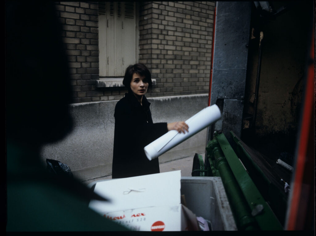 Julie (Juliette Binoche) throws sheet music into the garbage truck with an unfinished composition of her deceased husband.