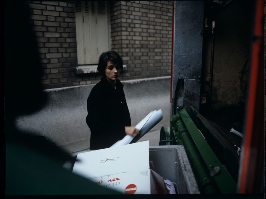 Julie (Juliette Binoche) throws sheet music into the garbage truck with an unfinished composition of her deceased husband.