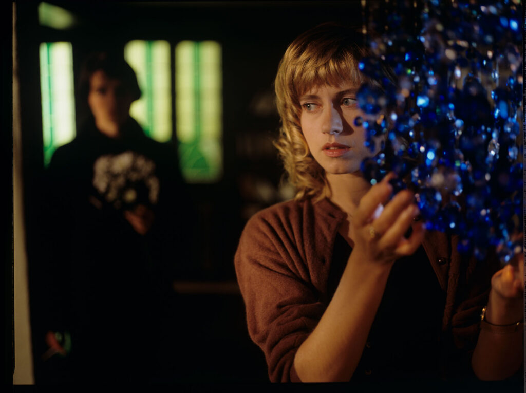 Lucille (Charlotte Very), Julie's neighbour, who works in a night club, looking at the blue chandellier.