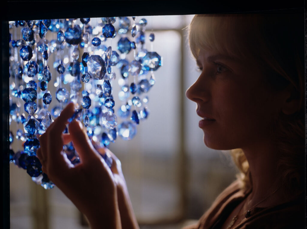 Lucille (Charlotte Very) looking at the blue chandellier, which Julie hung in her new apartment in Paris