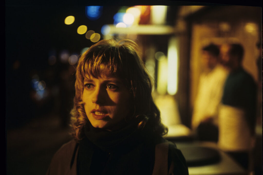 Lucille (Charlotte Very), Julie's neighbor who works at a nightclub, on a Parisian street.