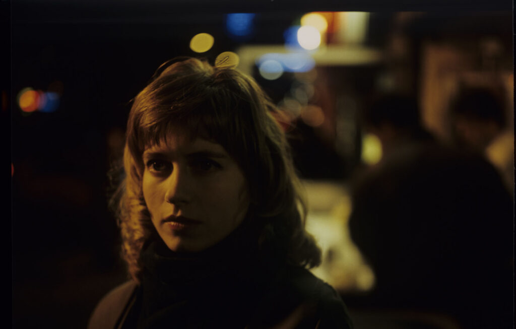 Lucille (Charlotte Very), Julie's neighbor who works at a nightclub, on a Parisian street.