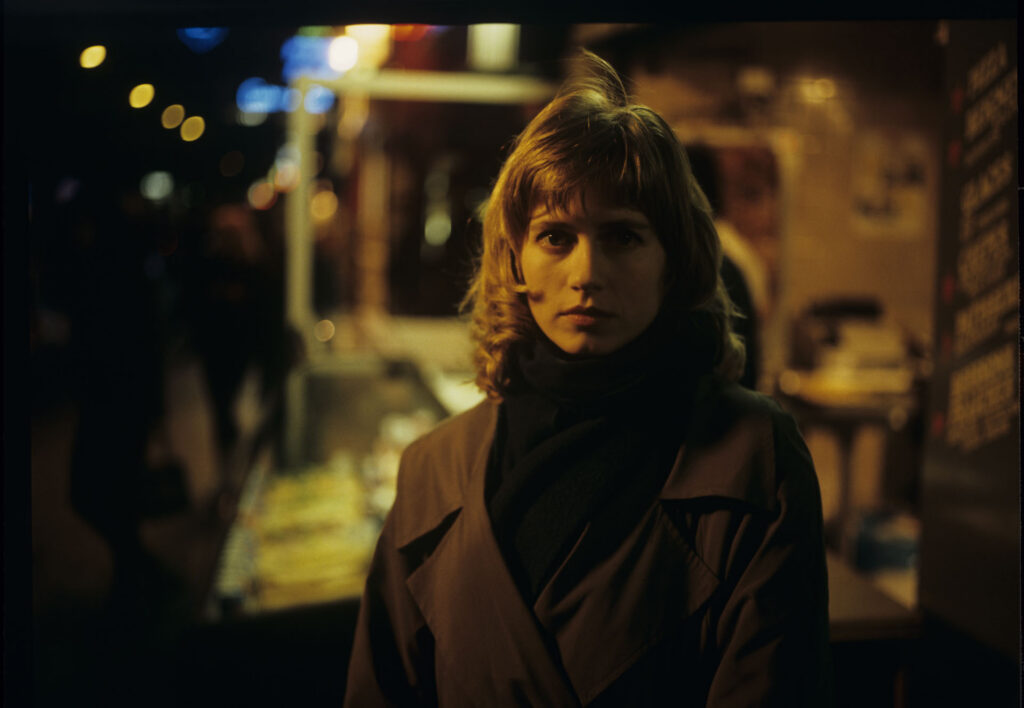 Lucille (Charlotte Very), Julie's neighbor who works at a nightclub, on a Parisian street.