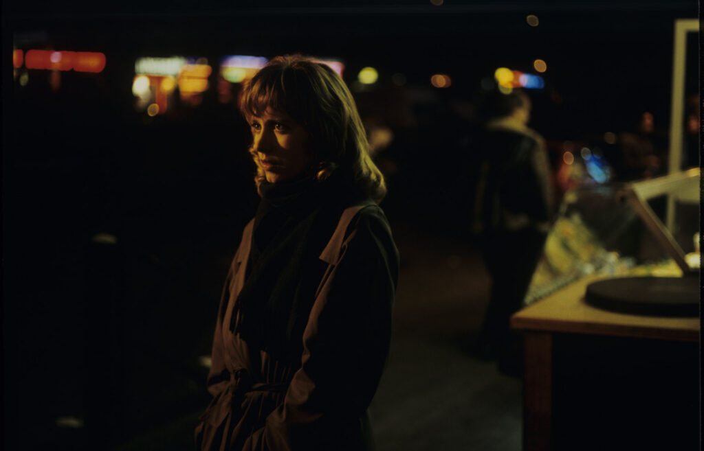 Lucille (Charlotte Very), Julie's neighbor who works at a nightclub, on a Parisian street.