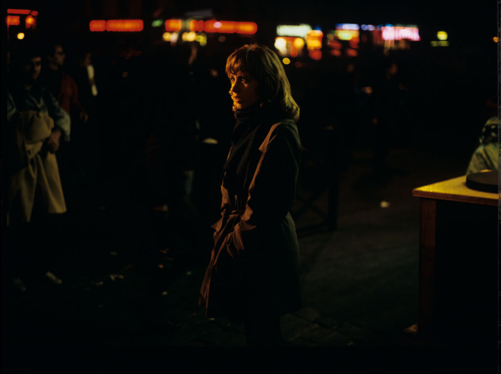 Lucille (Charlotte Very), Julie's neighbor who works at a nightclub, on a Parisian street.