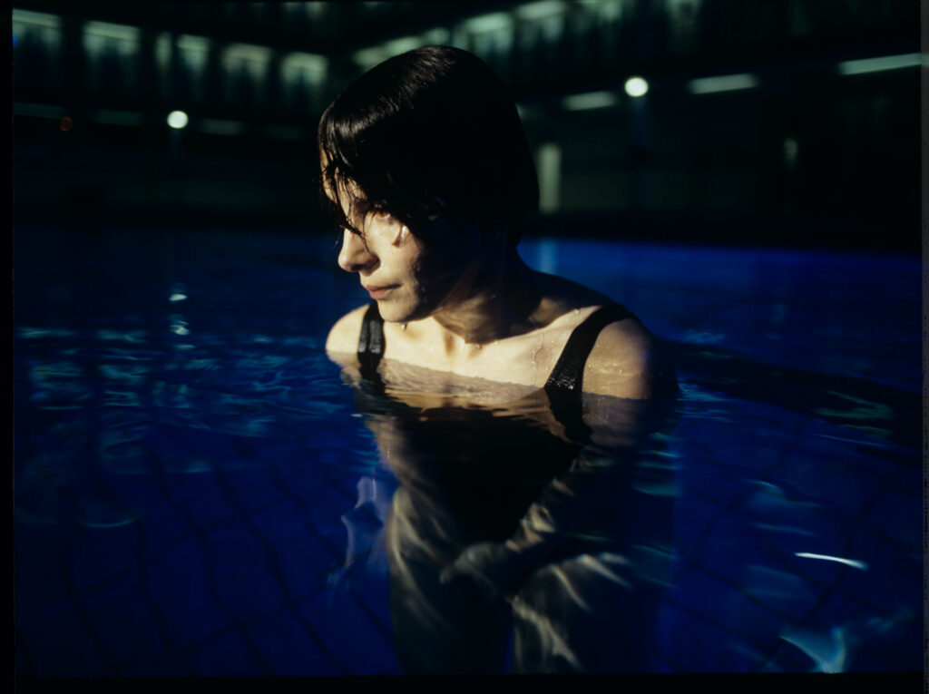 Julie (Juliette Binoche) in a blue glow, where she releases accumulated emotions while swimming.