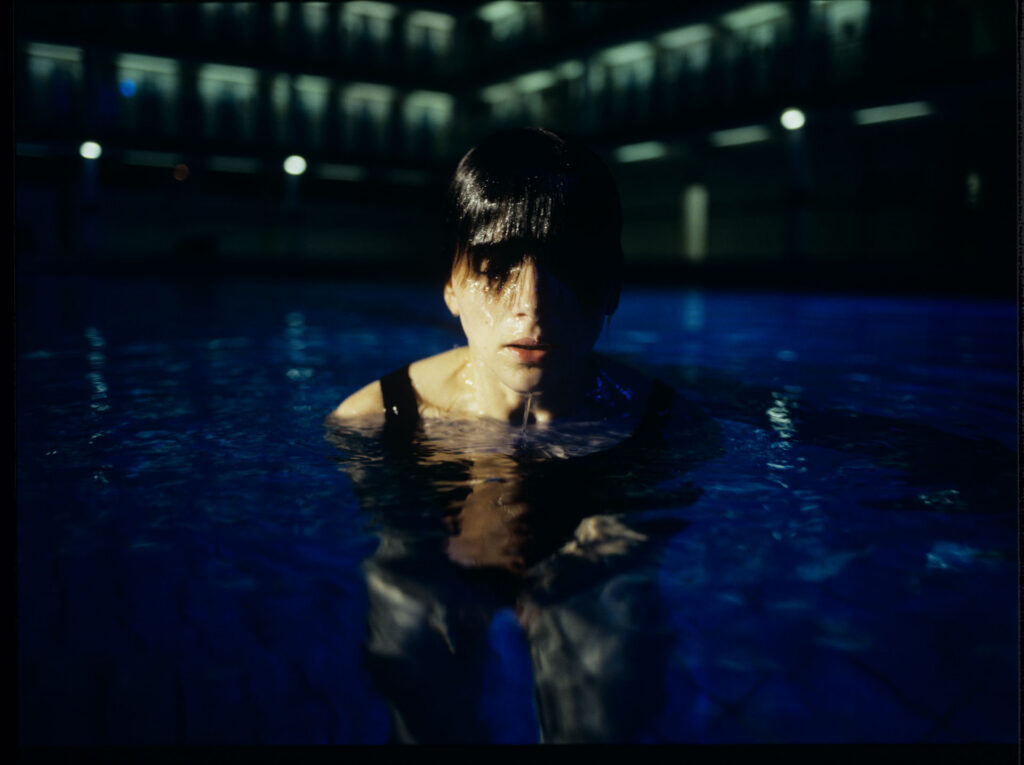 Julie (Juliette Binoche) in a blue glow, where she releases accumulated emotions while swimming.