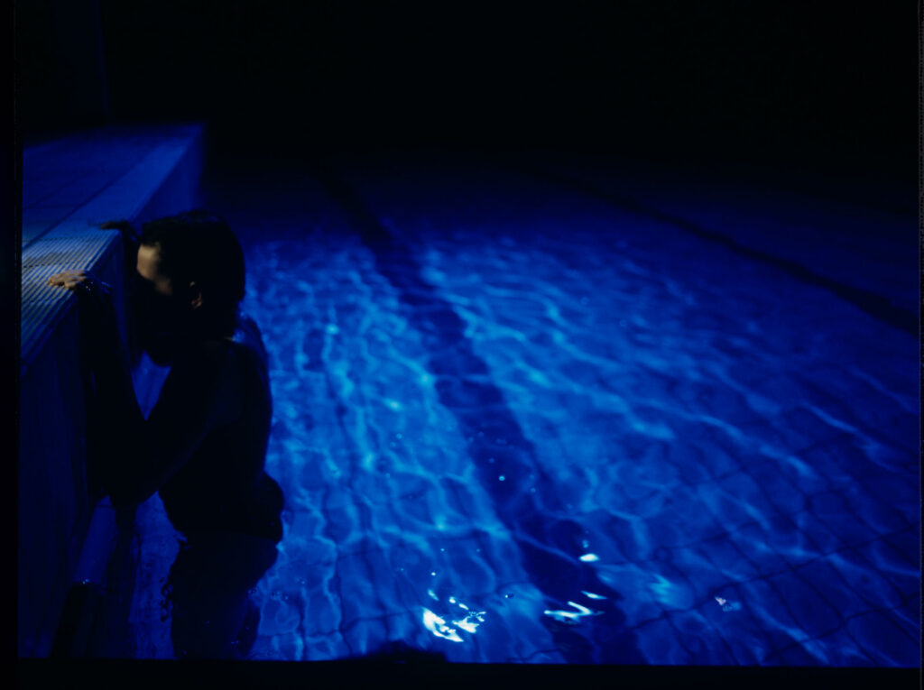 Julie (Juliette Binoche) in a blue glow, where she releases accumulated emotions while swimming.