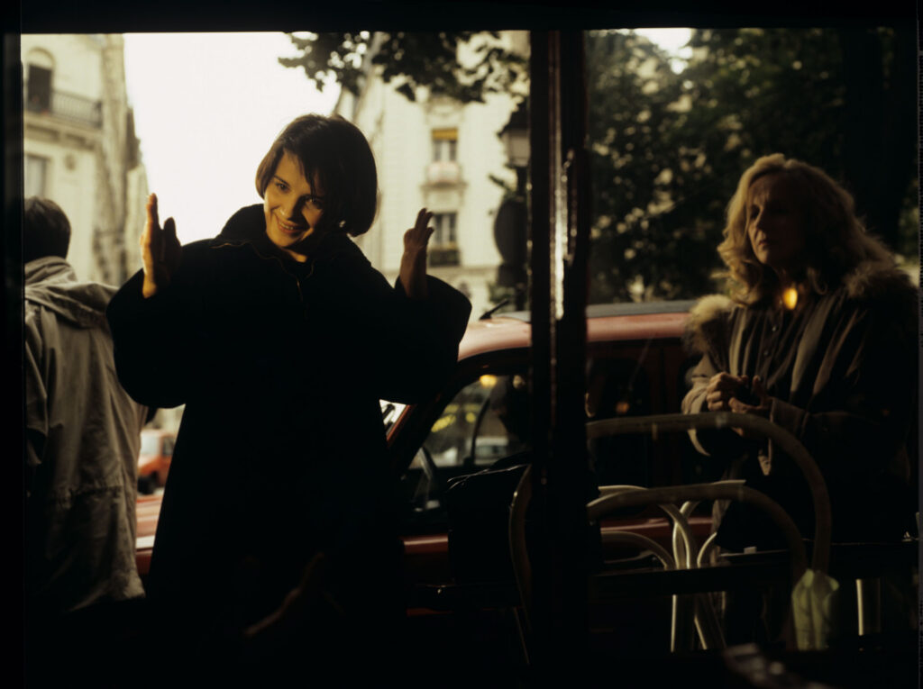 Julie (Juliette Binoche) is talking to a journalist (Helene Vincent) through her car window.