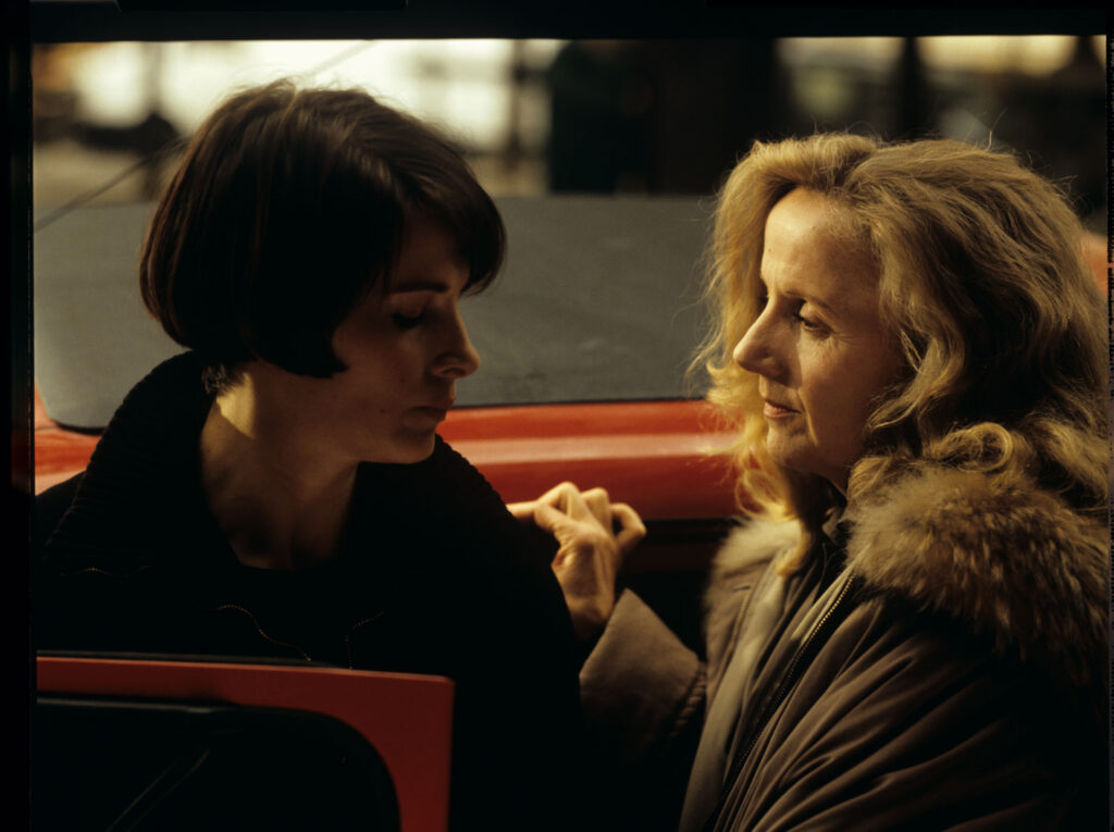 Julie (Juliette Binoche) is talking to a journalist (Helene Vincent) through her car window.