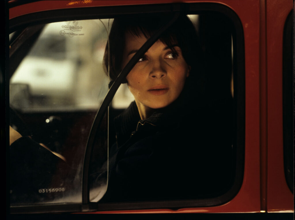 Julie (Juliette Binoche) is talking to a journalist (Helene Vincent) through her car window.