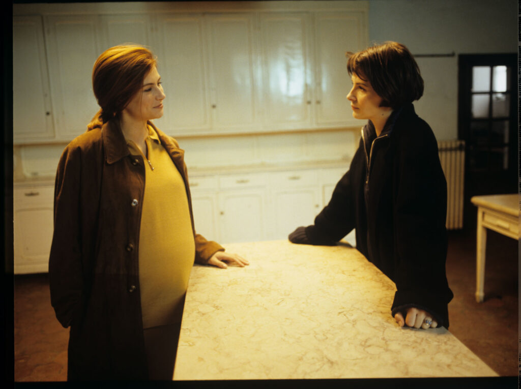 Sandrine (Florence Pernel) and Julie (Juliette Binoche) are talking in the kitchen of Julie and Patrice's suburban house